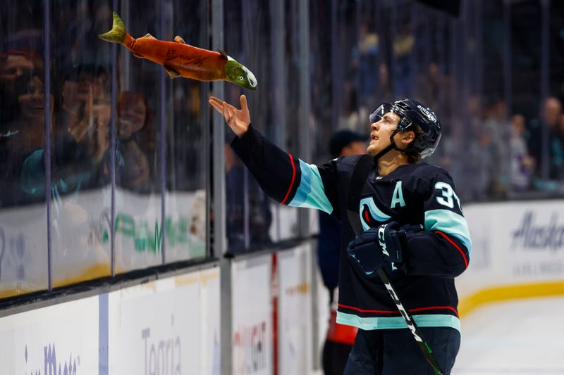 Oct 1, 2022; Seattle, Washington, USA; Seattle Kraken center Yanni Gourde (37) tosses a toy sockeye salmon to fans following a 4-0 victory against the Vancouver Canucks at Climate Pledge Arena. Mandatory Credit: Joe Nicholson-USA TODAY Sports