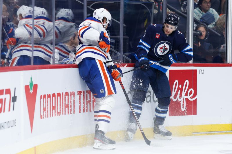 Sep 25, 2024; Winnipeg, Manitoba, CAN; Edmonton Oilers forward Mattias Janmark (13) and Winnipeg Jets defenseman Colin Miller (6) battle along the boards during the first period at Canada Life Centre. Mandatory Credit: Terrence Lee-Imagn Images