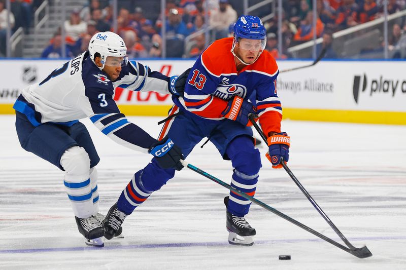 Sep 26, 2025; Edmonton, Alberta, CAN; Winnipeg Jets defensemen Isaak Phillips (3) tries to knock the puck away from Edmonton Oilers forward Mattias Janmark (13) during the first period at Rogers Place. Mandatory Credit: Perry Nelson-Imagn Images