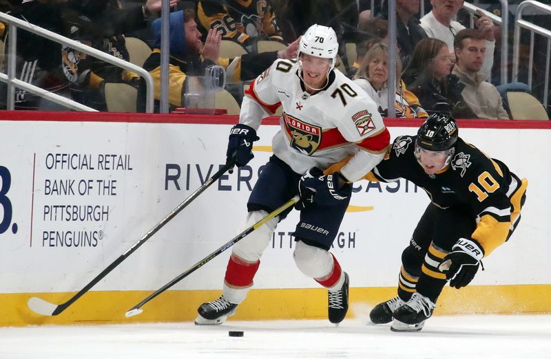 Dec 3, 2024; Pittsburgh, Pennsylvania, USA;  Florida Panthers center Jesper Boqvist (70) moves the puck against Pittsburgh Penguins left wing Drew O'Connor (10) during the second period at PPG Paints Arena. Mandatory Credit: Charles LeClaire-Imagn Images