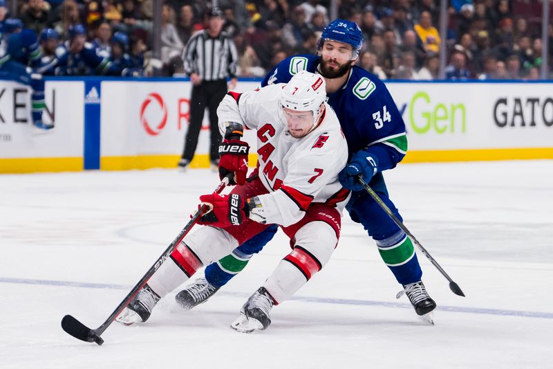 Dec 9, 2023; Vancouver, British Columbia, CAN; Vancouver Canucks forward Phillip Di Giuseppe (34) checks Carolina Hurricanes defenseman Dmitry Orlov (7) in the third period at Rogers Arena. Vancouver won 4-3. Mandatory Credit: Bob Frid-USA TODAY Sports