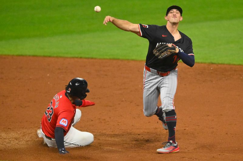 Sep 17, 2024; Cleveland, Ohio, USA; Minnesota Twins shortstop Brooks Lee (72) turns a double play beside Cleveland Guardians catcher Bo Naylor (23) in the fifth inning at Progressive Field. Mandatory Credit: David Richard-Imagn Images