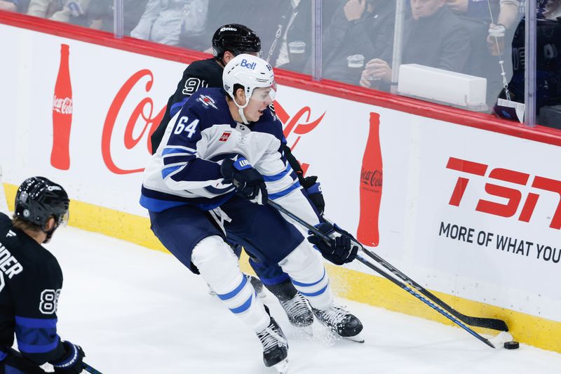 Oct 28, 2024; Winnipeg, Manitoba, CAN; Winnipeg Jets defenseman Logan Stanley (64) and Toronto Maple Leafs forward John Taveres (91) battle for the puck during the third period at Canada Life Centre. Mandatory Credit: Terrence Lee-Imagn Images