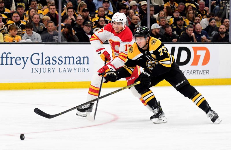 Nov 7, 2024; Boston, Massachusetts, USA;  Calgary Flames center Yegor Sharangovich (17) and Boston Bruins defenseman Charlie McAvoy (73) battle for the puck during the second period at TD Garden. Mandatory Credit: Bob DeChiara-Imagn Images