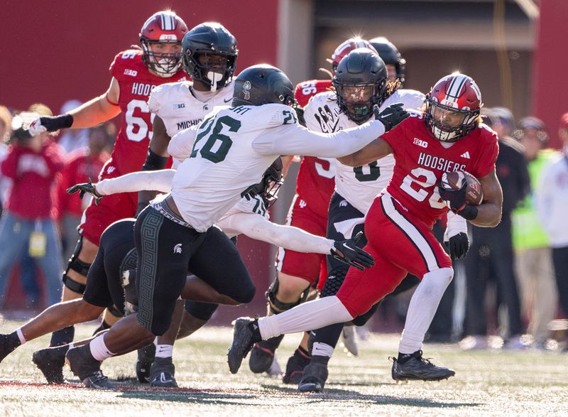 Nov 18, 2023; Bloomington, Indiana, USA; Indiana Hoosiers running back Josh Henderson (26) runs the ball past Michigan State Spartans defensive lineman Brandon Wright (26) during the second half at Memorial Stadium. Mandatory Credit: Marc Lebryk-USA TODAY Sports