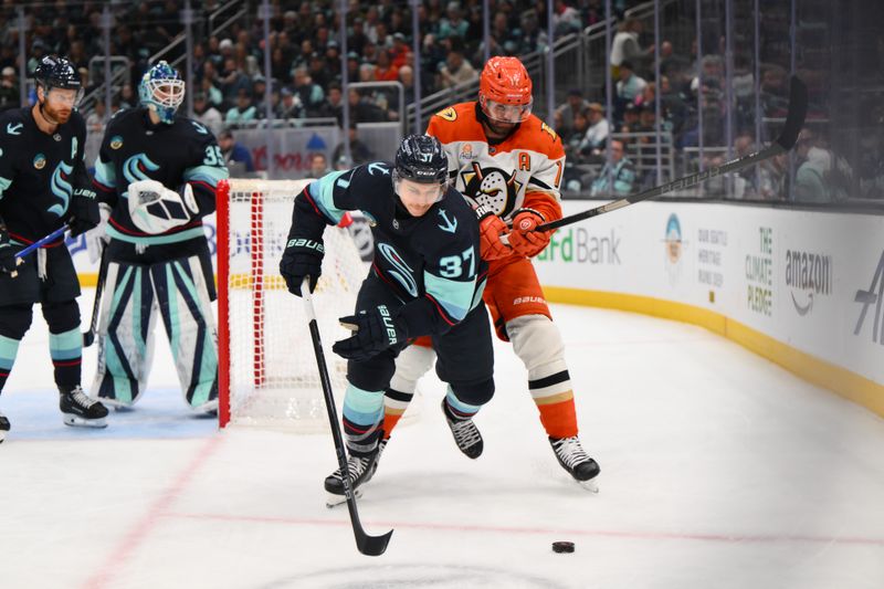 Nov 27, 2024; Seattle, Washington, USA; Seattle Kraken center Yanni Gourde (37) plays the puck while defended by Anaheim Ducks left wing Alex Killorn (17) during the second period at Climate Pledge Arena. Mandatory Credit: Steven Bisig-Imagn Images