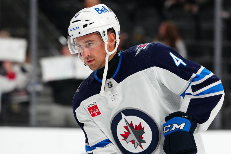 Nov 2, 2023; Las Vegas, Nevada, USA; Winnipeg Jets defenseman Neal Pionk (4) wears neck protection as he warms up before a game against the Vegas Golden Knights at T-Mobile Arena. Mandatory Credit: Stephen R. Sylvanie-USA TODAY Sports