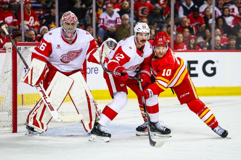 Dec 10, 2025; Calgary, Alberta, CAN; Calgary Flames left wing Jonathan Huberdeau (10) and Detroit Red Wings defenseman Travis Hamonic (52) fight for position in front of Detroit Red Wings goaltender John Gibson (36) during the second period at Scotiabank Saddledome. Mandatory Credit: Sergei Belski-Imagn Images