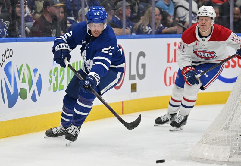 Sep 26, 2024; Toronto, Ontario, CAN;  Toronto Maple Leafs defenseman Jake McCabe (22) clears the puck away from Montreal Canadiens forward Emil Heineman (51) in the second period at Scotiabank Arena. Mandatory Credit: Dan Hamilton-Imagn Images