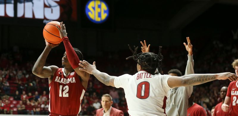 Mar 9, 2024; Tuscaloosa, Alabama, USA; Alabama guard Latrell Wrightsell Jr. (12) shoots a three with Arkansas guard Khalif Battle (0) defending at Coleman Coliseum. Alabama came from behind to win on overtime 92-88. Mandatory Credit: Gary Cosby Jr.-USA TODAY Sports