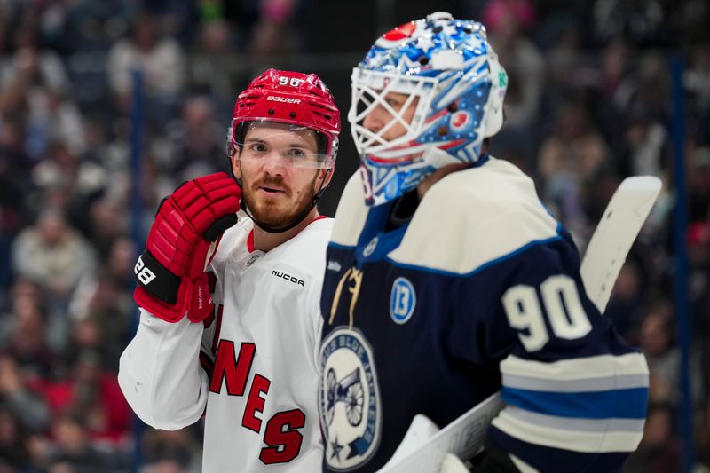 Nov 23, 2024; Columbus, Ohio, USA;  Carolina Hurricanes center Jack Roslovic (96) talks with Columbus Blue Jackets goaltender Elvis Merzlikins (90) during a stop in play in the first period at Nationwide Arena. Mandatory Credit: Aaron Doster-Imagn Images