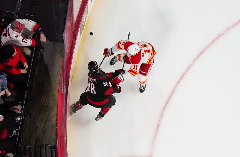 Mar 10, 2024; Raleigh, North Carolina, USA;  Calgary Flames center Mikael Backlund (11) checks Carolina Hurricanes left wing Jordan Martinook (48) during the first period at PNC Arena. Mandatory Credit: James Guillory-USA TODAY Sports