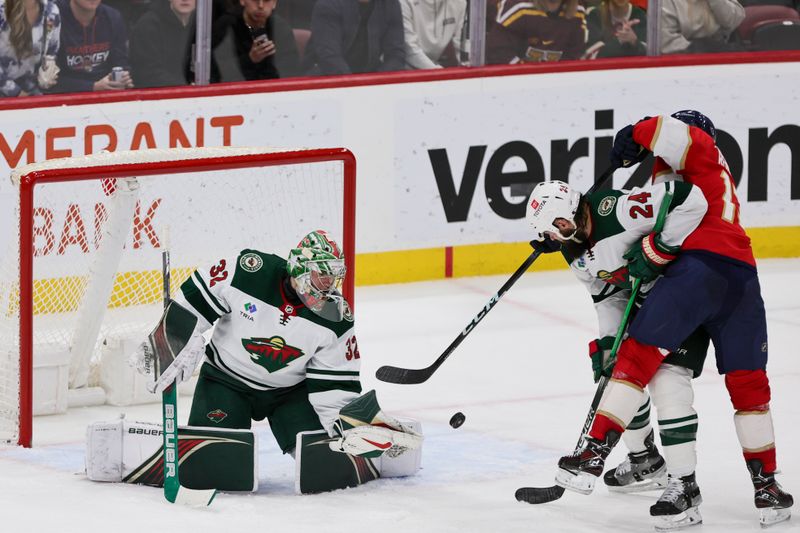 Jan 19, 2024; Sunrise, Florida, USA; Minnesota Wild goaltender Filip Gustavsson (32) defends his net as defenseman Zach Bogosian (24) battles for the puck against Florida Panthers center Sam Reinhart (13) during the third period at Amerant Bank Arena. Mandatory Credit: Sam Navarro-USA TODAY Sports