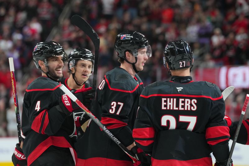 Nov 14, 2025; Raleigh, North Carolina, USA;  Carolina Hurricanes right wing Andrei Svechnikov (37) celebrates his goal with left wing Nikolaj Ehlers (27)  defenseman Shayne Gostisbehere (4) and center Sebastian Aho (20) against the Vancouver Canucks during the first period at Lenovo Center. Mandatory Credit: James Guillory-Imagn Images