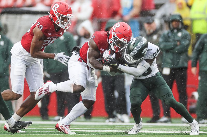 Oct 14, 2023; Piscataway, New Jersey, USA; Rutgers Scarlet Knights running back Kyle Monangai (5) is tackled by Michigan State Spartans defensive back Chance Rucker (25) in front of wide receiver Ian Strong (29) during the second half at SHI Stadium. Mandatory Credit: Vincent Carchietta-USA TODAY Sports