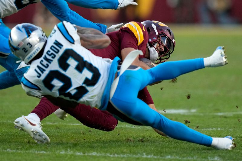 Washington Commanders quarterback Marcus Mariota is tackled by Carolina Panthers cornerback Dane Jackson (23) during the second half of an NFL football game, Sunday, Oct. 20, 2024, in Landover, Md. (AP Photo/Stephanie Scarbrough)