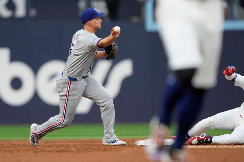 Jul 26, 2024; Toronto, Ontario, CAN; Texas Rangers shortstop Corey Seager (5) misses stepping on the bag to force out Toronto Blue Jays first baseman Vladimir Guerrero Jr. (27) before throwing to first base during the first inning at Rogers Centre. Mandatory Credit: John E. Sokolowski-USA TODAY Sports