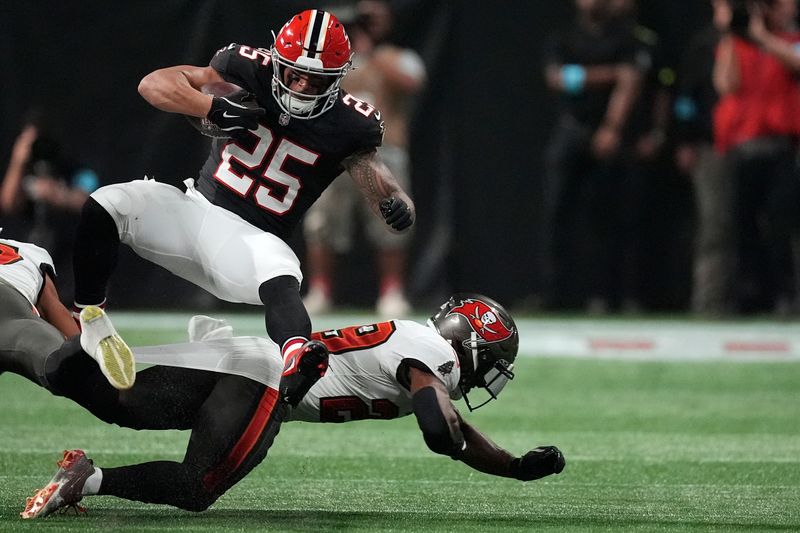 Atlanta Falcons running back Tyler Allgeier (25) is tripped up by Tampa Bay Buccaneers safety Christian Izien (29) during the first half of an NFL football game Thursday, Oct. 3, 2024, in Atlanta. (AP Photo/John Bazemore)