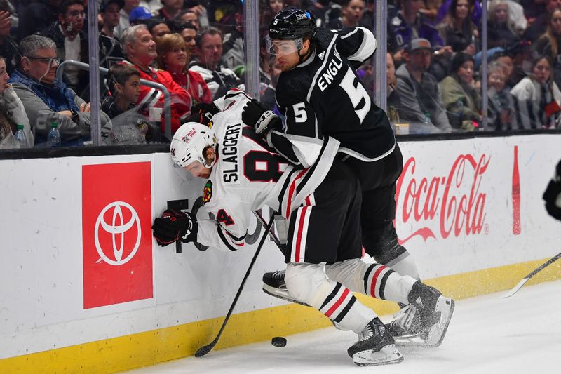 Apr 18, 2024; Los Angeles, California, USA; Los Angeles Kings defenseman Andreas Englund (5) hits Chicago Blackhawks left wing Landon Slaggert (84) while playing for the puck during the third period at Crypto.com Arena. Mandatory Credit: Gary A. Vasquez-USA TODAY Sports