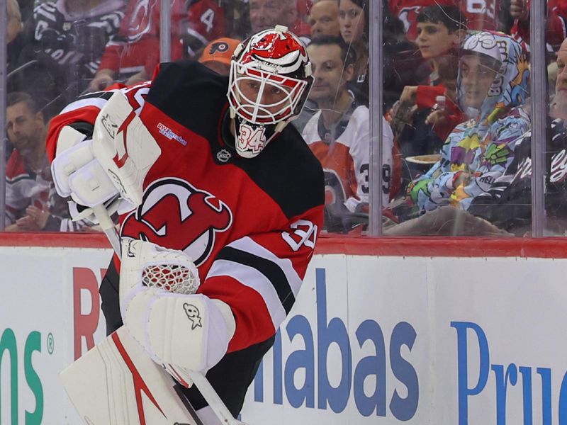 Jan 18, 2025; Newark, New Jersey, USA; New Jersey Devils goaltender Jake Allen (34) plays the puck against the Philadelphia Flyers during the first period at Prudential Center. Mandatory Credit: Ed Mulholland-Imagn Images