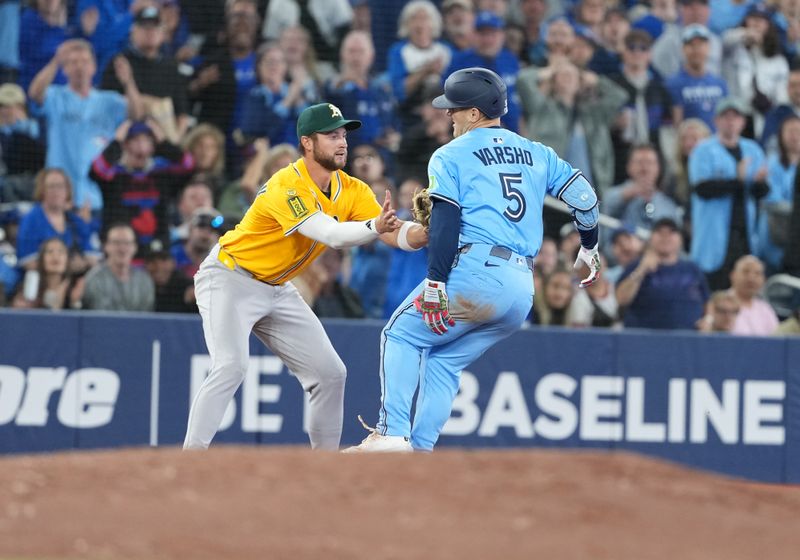 May 31, 2025; Toronto, Ontario, CAN; Athletics third baseman Max Schuemann (12) tags out Toronto Blue Jays centre fielder Daulton Varsho (5) after grabbing his left leg after rounding second base against the Athletics during the third inning at Rogers Centre. Mandatory Credit: Nick Turchiaro-Imagn Images