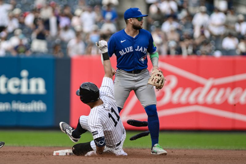 Sep 6, 2025; Bronx, New York, USA; New York Yankees shortstop Anthony Volpe (11) slides into second base with a double as Toronto Blue Jays shortstop Isiah Kiner-Falefa (7) awaits the throw during the sixth inning at Yankee Stadium. Mandatory Credit: John Jones-Imagn Images