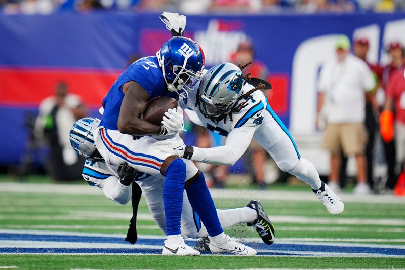 New York Giants wide receiver Parris Campbell, left, is tackled by Carolina Panthers linebacker Shaq Thompson, right, and safety Vonn Bell, rear, during an NFL pre-season football game on Friday, Aug. 18, 2023, in East Rutherford, N.J. (AP Photo/Rusty Jones)