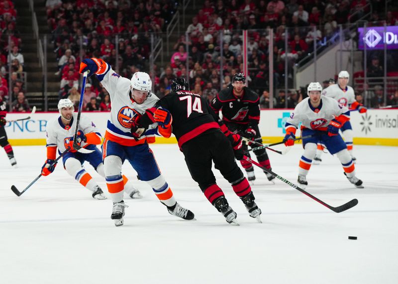 Apr 30, 2024; Raleigh, North Carolina, USA; New York Islanders center Bo Horvat (14) tries to get to the puck against the check by Carolina Hurricanes defenseman Jaccob Slavin (74) during the second period in game five of the first round of the 2024 Stanley Cup Playoffs at PNC Arena. Mandatory Credit: James Guillory-USA TODAY Sports