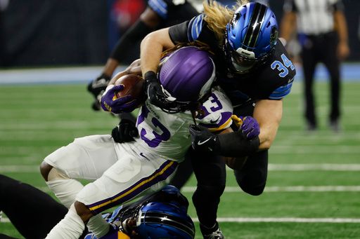 Minnesota Vikings cornerback Fabian Moreau (23) is tackled by Detroit Lions defensive end Za'Darius Smith (99) and linebacker Alex Anzalone (34) in the first half of an NFL football game in Detroit, Sunday, Jan. 5, 2025. (AP Photo/Rick Osentoski)