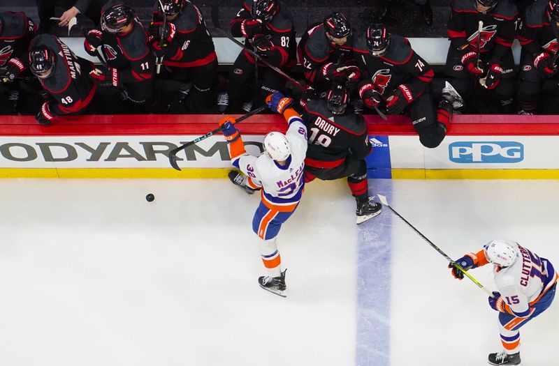 Apr 20, 2024; Raleigh, North Carolina, USA; Carolina Hurricanes center Jack Drury (18) is checked by New York Islanders center Kyle MacLean (32) during the first period in game one of the first round of the 2024 Stanley Cup Playoffs at PNC Arena. Mandatory Credit: James Guillory-USA TODAY Sports