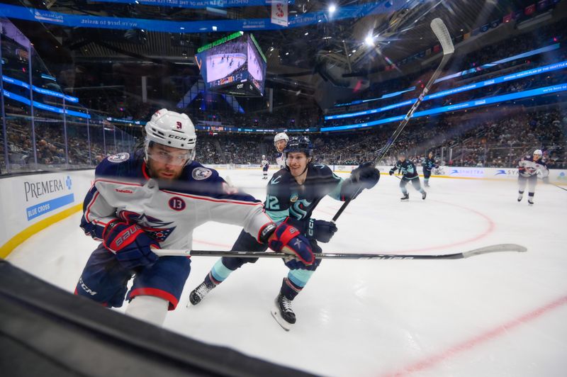 Nov 12, 2024; Seattle, Washington, USA; Columbus Blue Jackets defenseman Jack Johnson (3) plays the puck off the boards while defended by Seattle Kraken left wing Tye Kartye (12) during the second period at Climate Pledge Arena. Mandatory Credit: Steven Bisig-Imagn Images