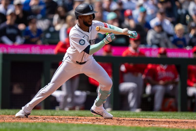 Apr 30, 2025; Seattle, Washington, USA;  Seattle Mariners right fielder Samad Taylor (0) bunts for a base hit seventh inning against the Los Angeles Angels at T-Mobile Park. Mandatory Credit: Stephen Brashear-Imagn Images