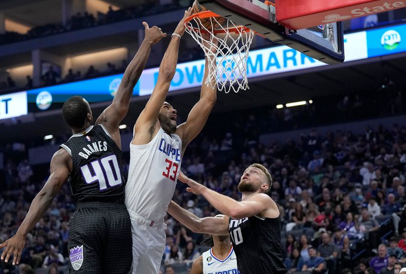 SACRAMENTO, CALIFORNIA - OCTOBER 22: Nicolas Batum #33 of the LA Clippers dunks over Harrison Barnes #40 and Domantas Sabonis #10 of the Sacramento Kings during the first quarter of the game at Golden 1 Center on October 22, 2022 in Sacramento, California. NOTE TO USER: User expressly acknowledges and agrees that, by downloading and or using this photograph, User is consenting to the terms and conditions of the Getty Images License Agreement. (Photo by Thearon W. Henderson/Getty Images)