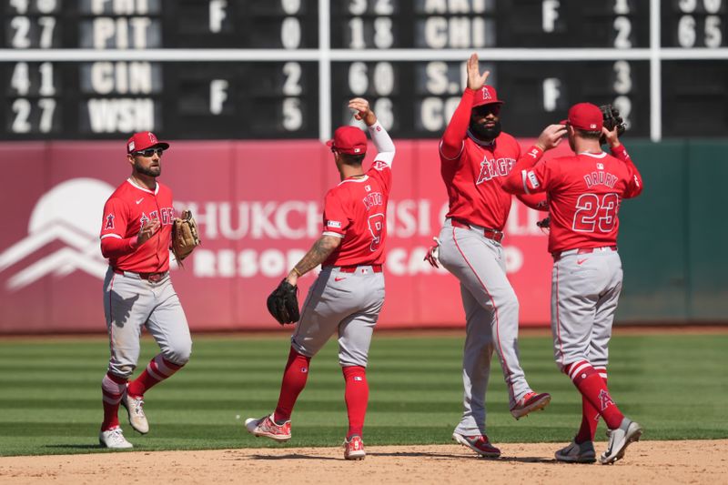 Jul 21, 2024; Oakland, California, USA; (L to R) Los Angeles Angels center fielder Kevin Pillar celebrates on the field with shortstop Zach Neto (9) and right fielder Jo Adell (7) and second baseman Brandon Drury (23) after defeating the Oakland Athletics at Oakland-Alameda County Coliseum. Mandatory Credit: Darren Yamashita-USA TODAY Sports