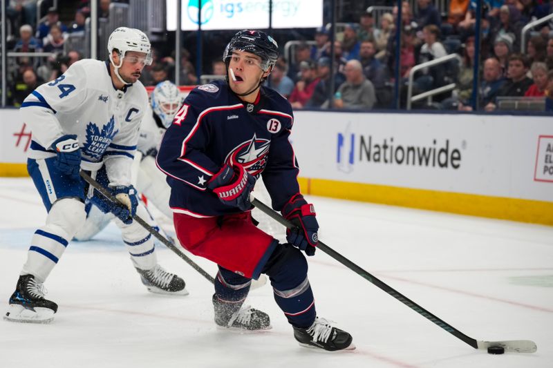 Oct 22, 2024; Columbus, Ohio, USA; Columbus Blue Jackets center Cole Sillinger (4) reacts as he skates with the puck against Toronto Maple Leafs center Auston Matthews (34) during the second period at Nationwide Arena. Mandatory Credit: Aaron Doster-Imagn Images