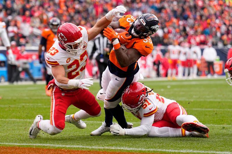 Denver Broncos running back Javonte Williams (33) scores past Kansas City Chiefs linebacker Drue Tranquill (23) and Mike Danna (51) during the first half of an NFL football game Sunday, Oct. 29, 2023, in Denver. (AP Photo/Jack Dempsey)