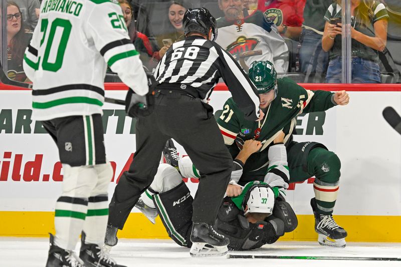 Sep 29, 2024; Saint Paul, Minnesota, USA;  Minnesota Wild forward Brendan Gaunce (21) fights Dallas Stars forward Mathias Emilio Pettersen (37) during the first period at Xcel Energy Center. Mandatory Credit: Nick Wosika-Imagn Images