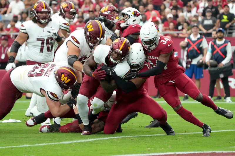 Washington Commanders running back Brian Robinson Jr., center, runs in for a touchdown as Arizona Cardinals linebacker Kyzir White (7) defends during the first half of an NFL football game, Sunday, Sept. 29, 2024, in Glendale, Ariz. (AP Photo/Rick Scuteri)