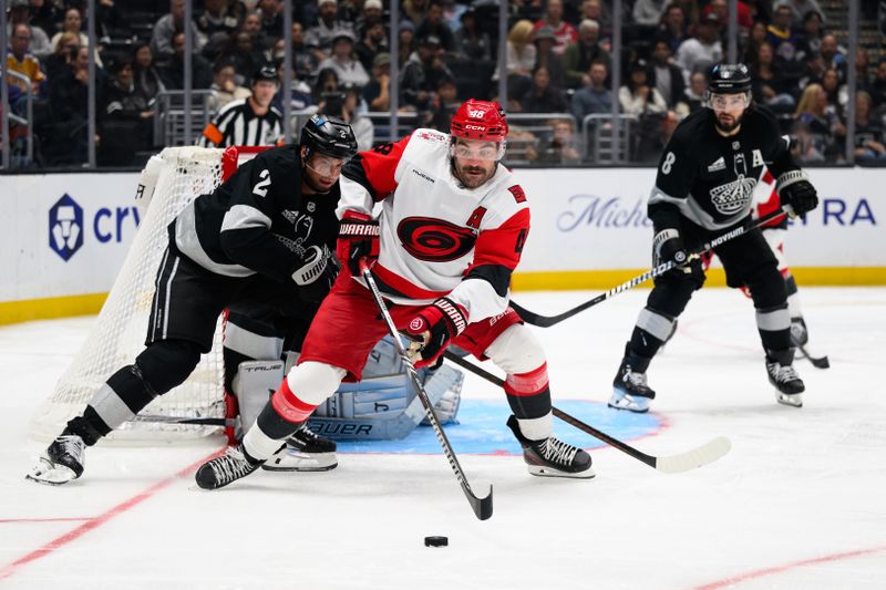 Oct 18, 2025; Los Angeles, California, USA; Carolina Hurricanes left wing Jordan Martinook (48) controls the puck under pressure from Los Angeles Kings defenseman Brian Dumoulin (2) during the third period at Crypto.com Arena. Mandatory Credit: William Liang-Imagn Images
