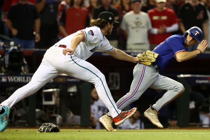 Nov 1, 2023; Phoenix, Arizona, USA; Texas Rangers center fielder Evan Carter (32) is tagged out by Arizona Diamondbacks relief pitcher Kevin Ginkel (37) after overrunning the base during the seventh inning in game five of the 2023 World Series at Chase Field. Mandatory Credit: Mark J. Rebilas-USA TODAY Sports