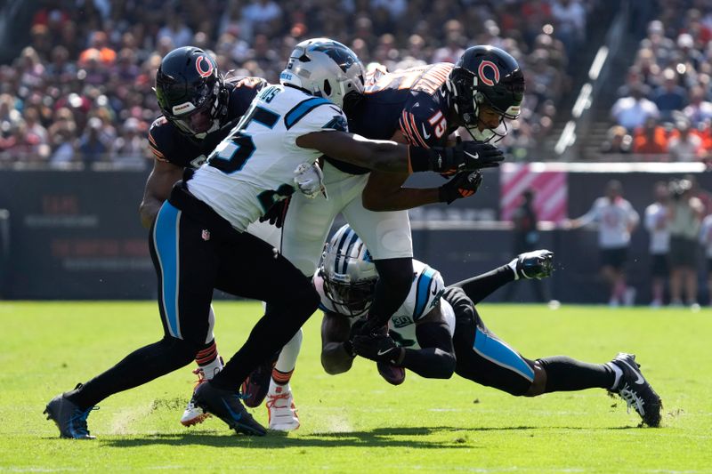 Chicago Bears wide receiver Rome Odunze (15) is brought down by Carolina Panthers safety Xavier Woods (25) and Jaycee Horn (8) during the first half of an NFL football game Sunday, Oct. 6, 2024, in Chicago. (AP Photo/Nam Y. Huh)