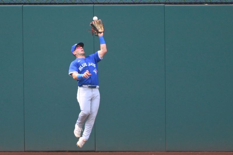 Jun 22, 2024; Cleveland, Ohio, USA; Toronto Blue Jays left fielder Daulton Varsho (25) makes a catch on the warning track in the second inning against the Cleveland Guardians at Progressive Field. Mandatory Credit: David Richard-USA TODAY Sports