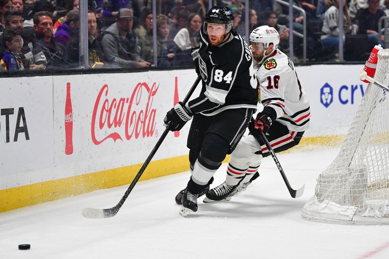 Apr 18, 2024; Los Angeles, California, USA; Los Angeles Kings defenseman Vladislav Gavrikov (84) moves the puck ahead of Chicago Blackhawks center Jason Dickinson (16) during the third period at Crypto.com Arena. Mandatory Credit: Gary A. Vasquez-USA TODAY Sports