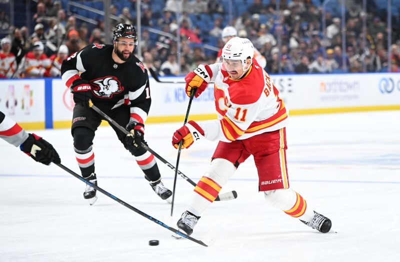 Nov 19, 2025; Buffalo, New York, USA; Calgary Flames center Mikael Backlund (11) shoots the puck as Buffalo Sabres left wing Jordan Greenway (12) defends in the third period at KeyBank Center. Mandatory Credit: Mark Konezny-Imagn Images