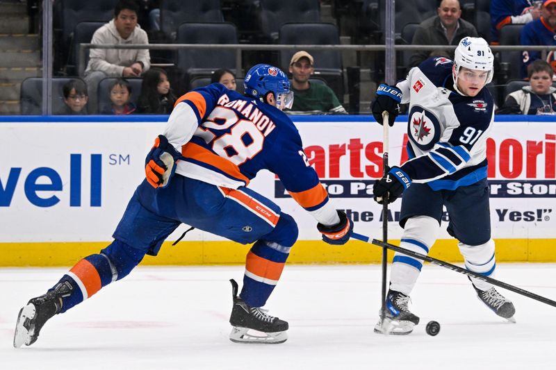 Mar 23, 2024; Elmont, New York, USA;  Winnipeg Jets center Cole Perfetti (91) attempts a shot defended by New York Islanders defenseman Alexander Romanov (28) during the first period at UBS Arena. Mandatory Credit: Dennis Schneidler-USA TODAY Sports