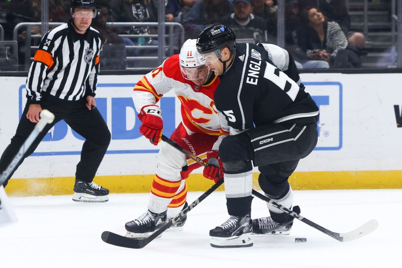 Dec 23, 2023; Los Angeles, California, USA; Los Angeles Kings defenseman Andreas Englund (5) and Calgary Flames center Mikael Backlund (11) fight for the puck during the third period of a game at Crypto.com Arena. Mandatory Credit: Jessica Alcheh-USA TODAY Sports