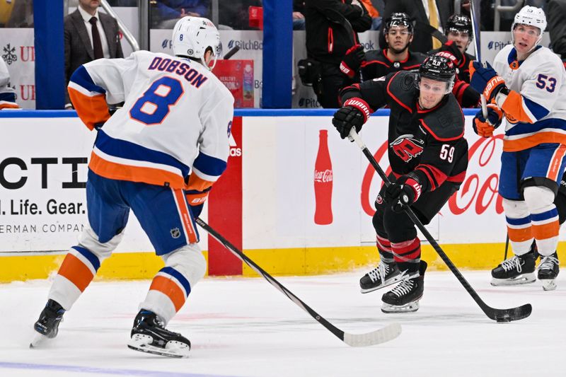 Mar 19, 2024; Elmont, New York, USA; Carolina Hurricanes left wing Jake Guentzel (59) shoots and scores on an empty net defended by New York Islanders defenseman Noah Dobson (8) during the third period at UBS Arena. Mandatory Credit: Dennis Schneidler-USA TODAY Sports