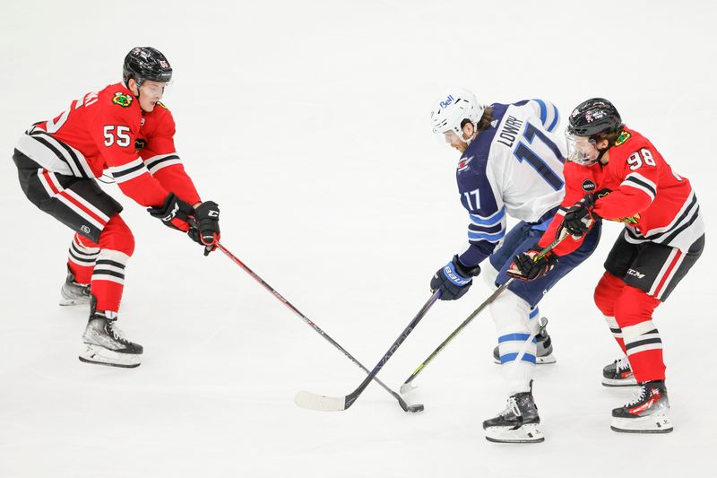 Feb 23, 2024; Chicago, Illinois, USA; Chicago Blackhawks defenseman Kevin Korchinski (55) and center Connor Bedard (98) battle for the puck with Winnipeg Jets center Adam Lowry (17) during the second period at United Center. Mandatory Credit: Kamil Krzaczynski-USA TODAY Sports