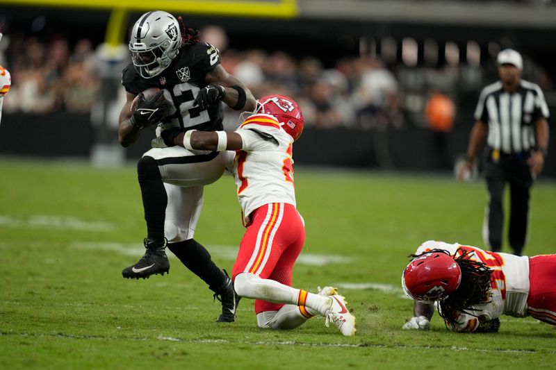 Kansas City Chiefs safety Chamarri Conner, right, reaches for Las Vegas Raiders running back Alexander Mattison (22) during the second half of an NFL football game Sunday, Oct. 27, 2024, in Las Vegas. (AP Photo/John Locher)