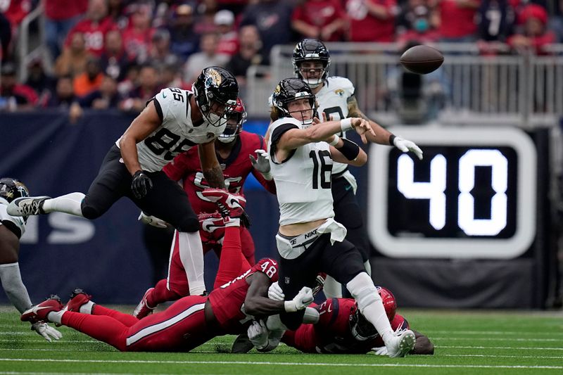 Jacksonville Jaguars quarterback Trevor Lawrence (16) throws an incomplete pass as he tackled by Houston Texans linebacker Christian Harris (48) in the first half of an NFL football game in Houston, Sunday, Nov. 26, 2023. (AP Photo/Eric Gay)